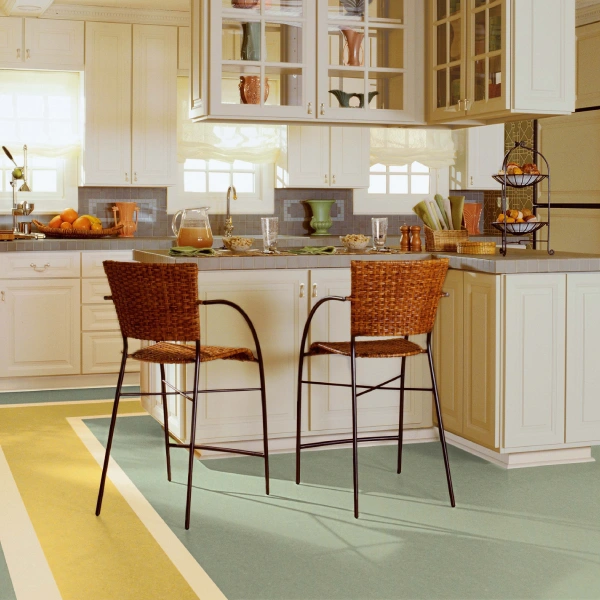 A kitchen featuring light-colored cabinets and a floor with broad stripes of light green and yellow, creating a geometric pattern.