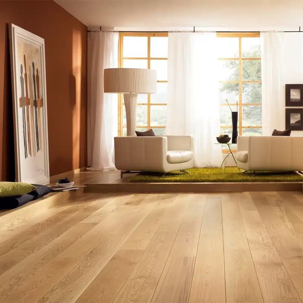 A bright room with polished light-colored wooden flooring leading to a raised platform with a green shag rug